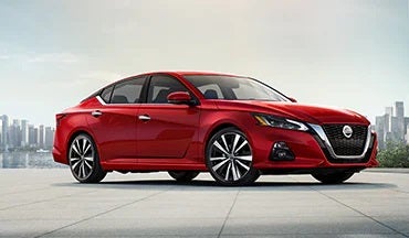 2023 Nissan Altima in red with city in background illustrating last year's 2022 model in Merchant Nissan in Troy AL